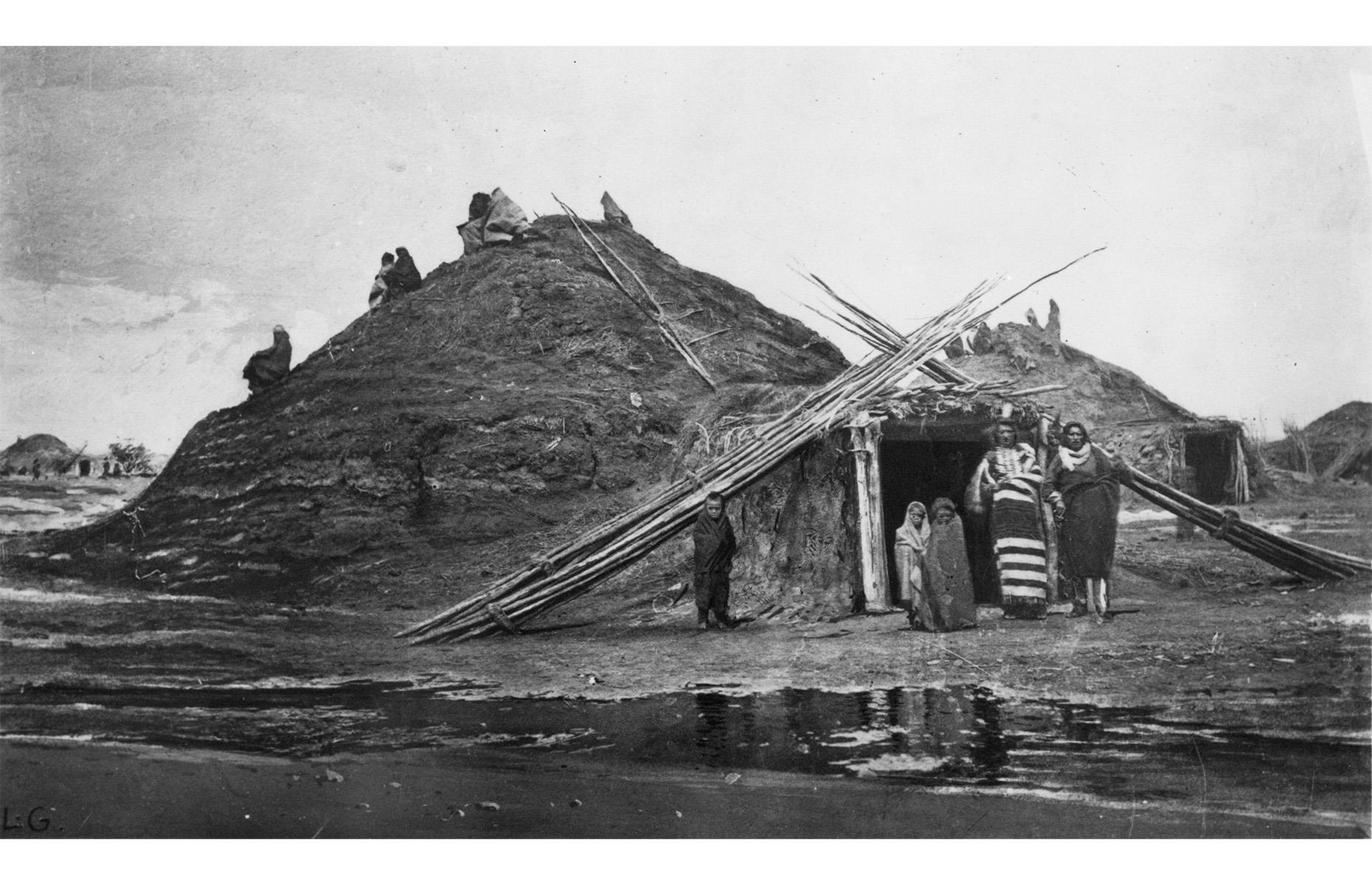 1871: Pawnee family standing in front of their earth lodge, Nebraska